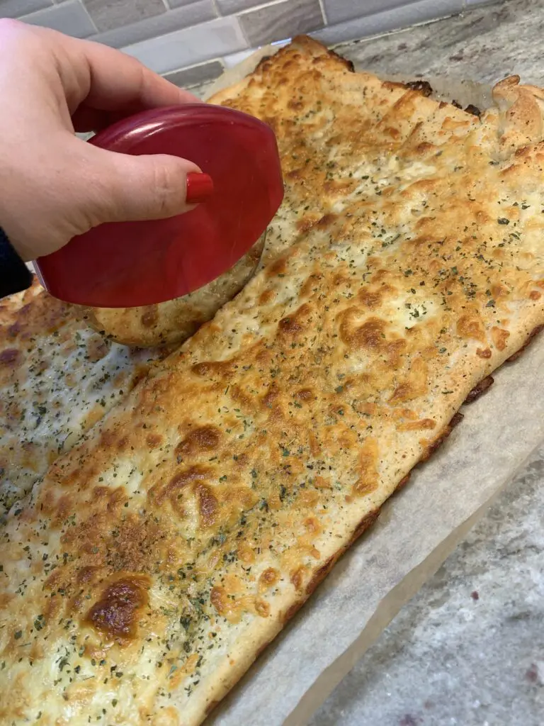 slicing the cooked easy cheesy garlic bread close up