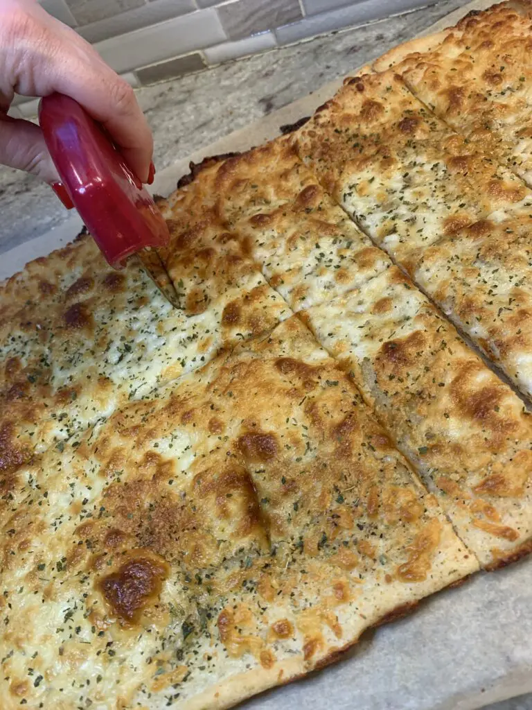 slicing the cooked easy cheesy garlic bread further out