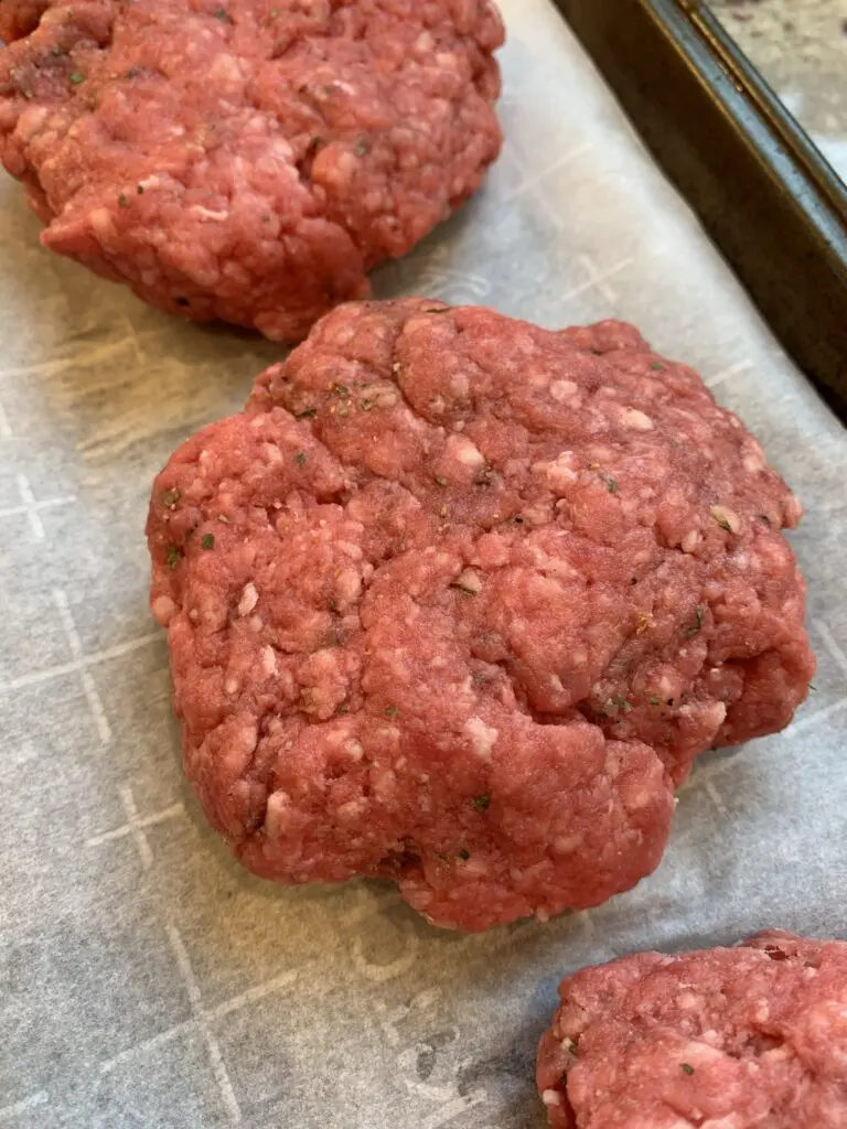 seasoned burgers on parchment paper
