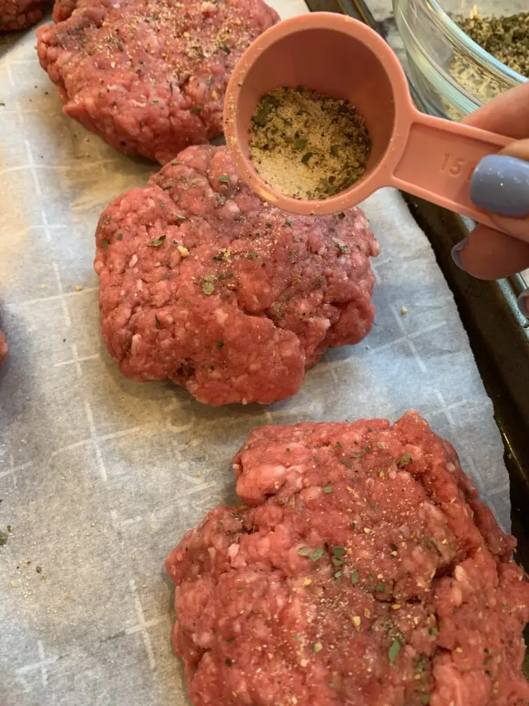 adding more seasoning to the burgers