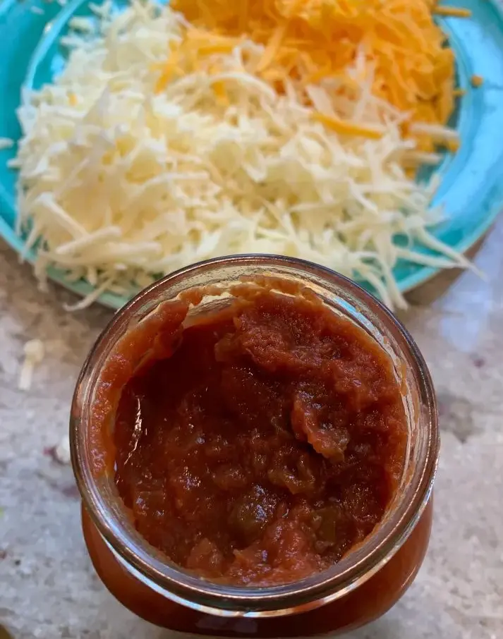 opened jar of salsa with shredded cheese