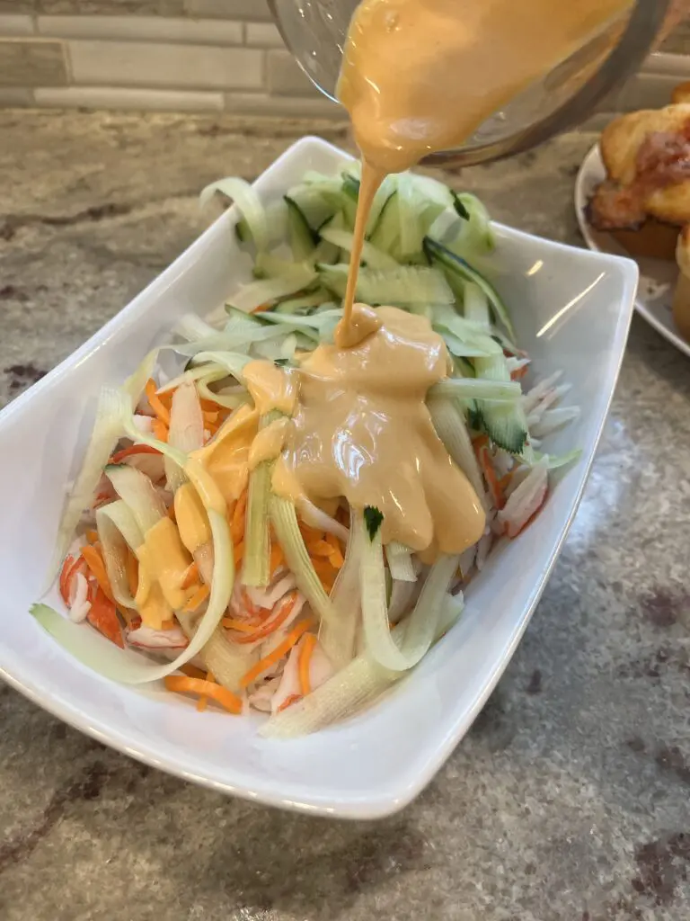 adding spicy mayo to the kani salad