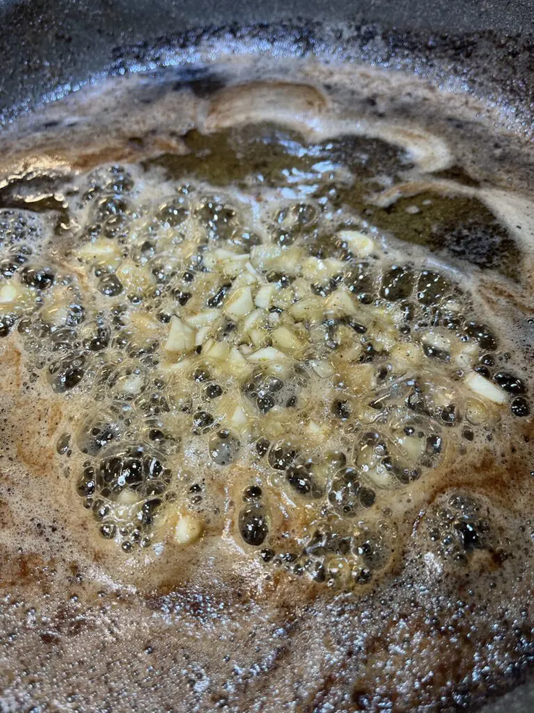 adding chopped garlic to pan sauce