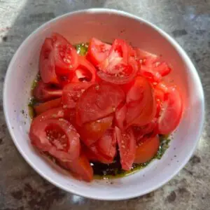 sliced tomatoes added to bowl