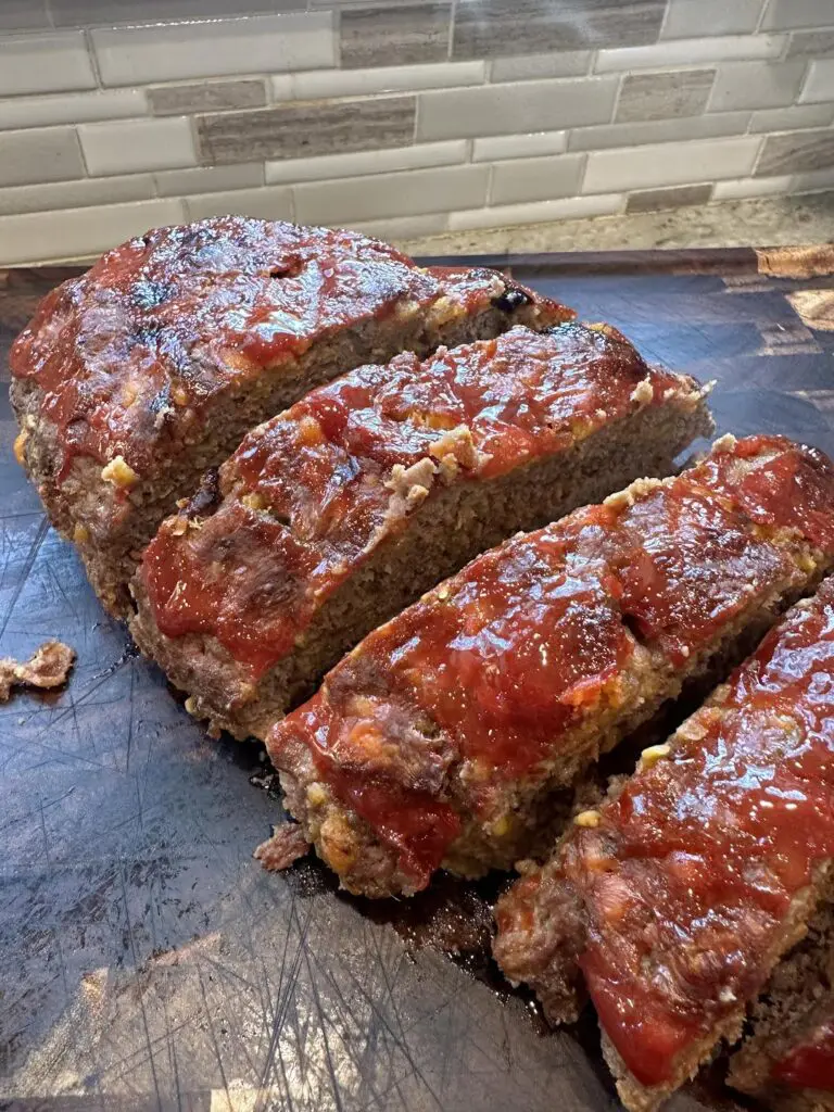 cooked bacon cheeseburger meatloaf on cutting board sliced