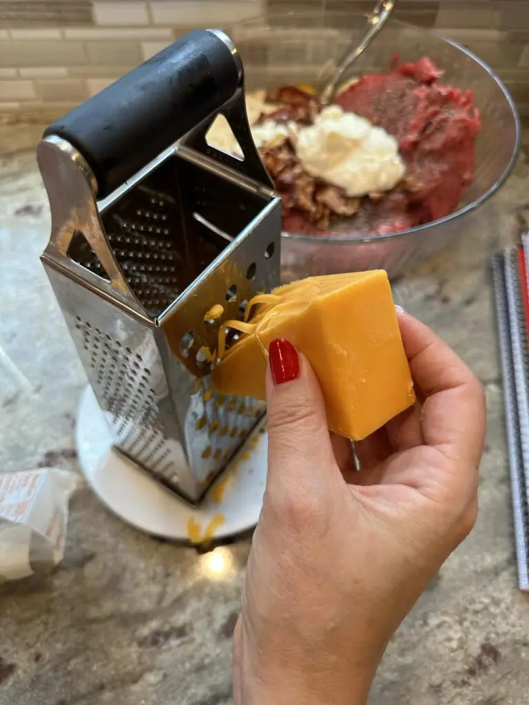 shredding block of cheese on grater by hand