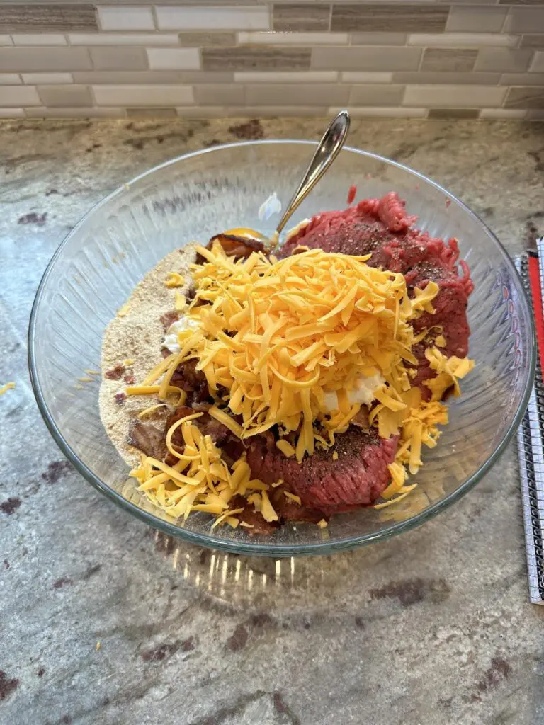 seasoned ground beef, shredded cheese, breadcrumbs, egg in bowl before mixing
