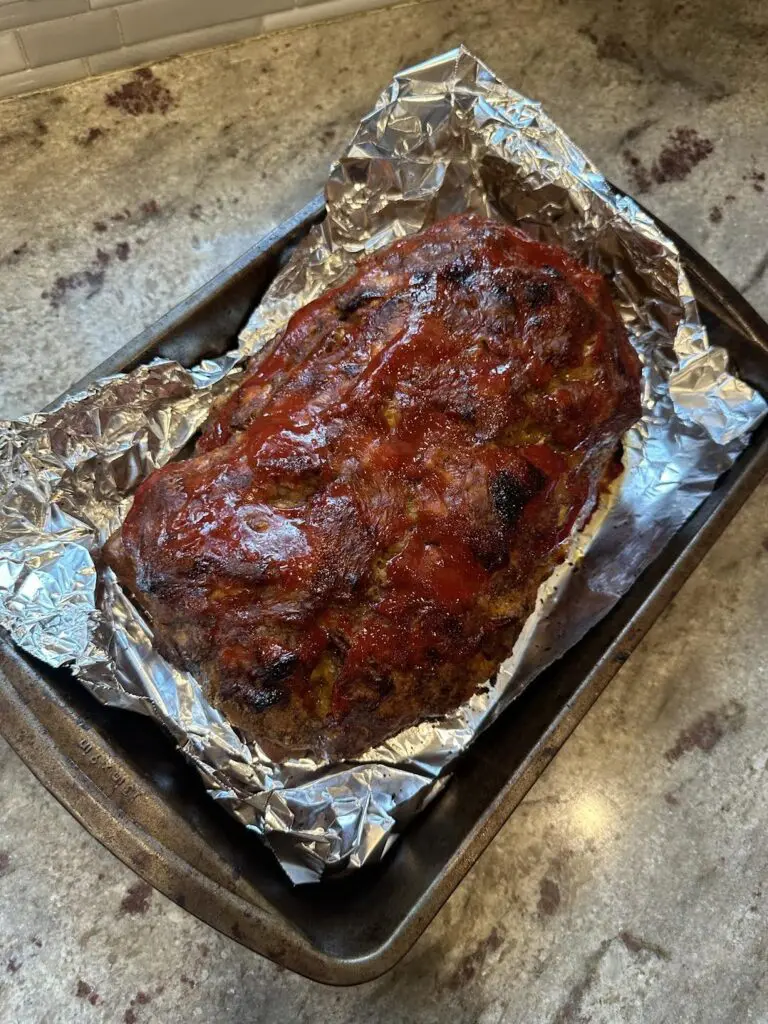 cooked bacon cheeseburger meatloaf on tray before slicing