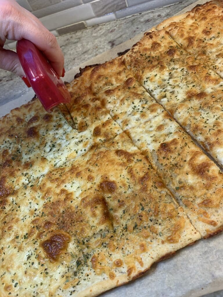 slicing the cooked easy cheesy garlic bread further out