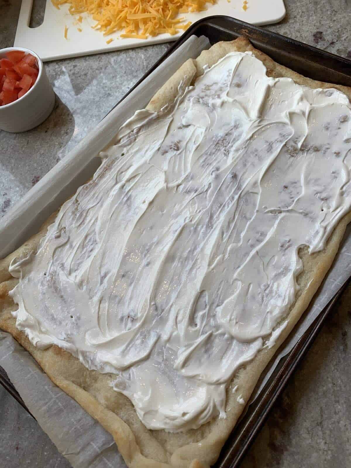 sour cream spread out over cooked pizza dough