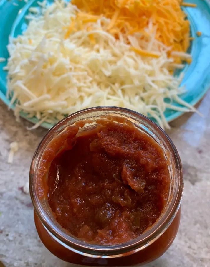 opened jar of salsa with shredded cheese