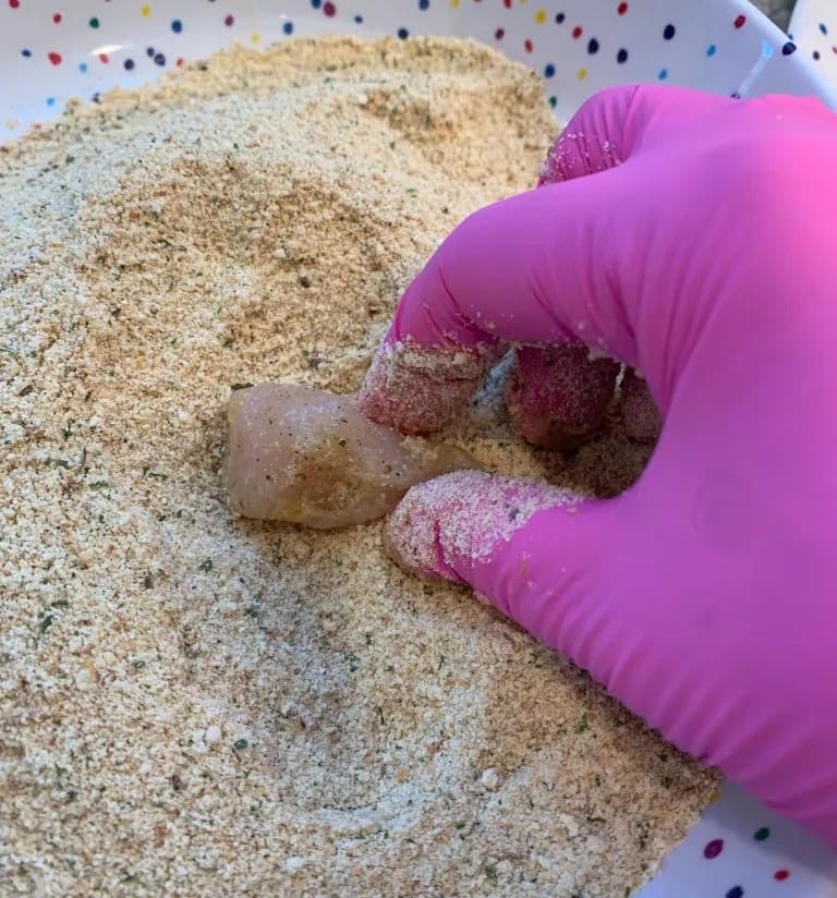 chicken going into seasoned breadcrumbs 
