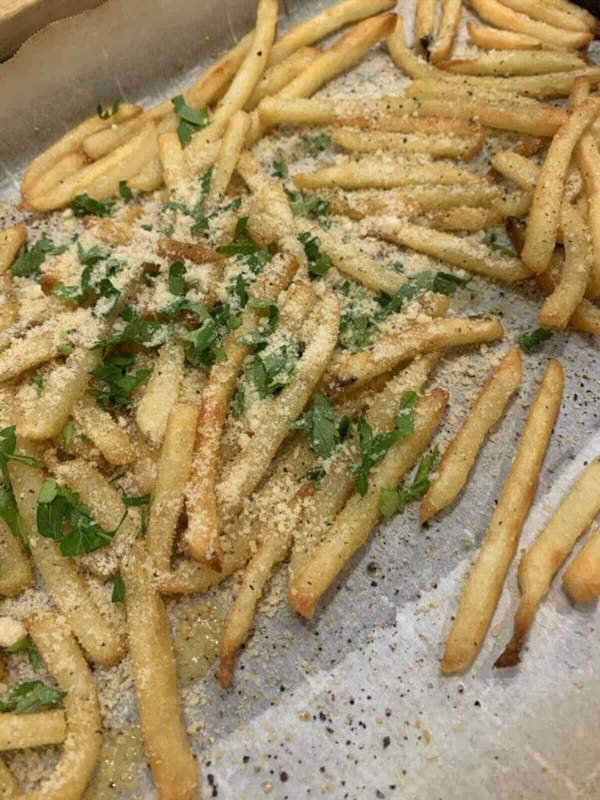fries on baking sheet covered in parmesan cheese and garlic
