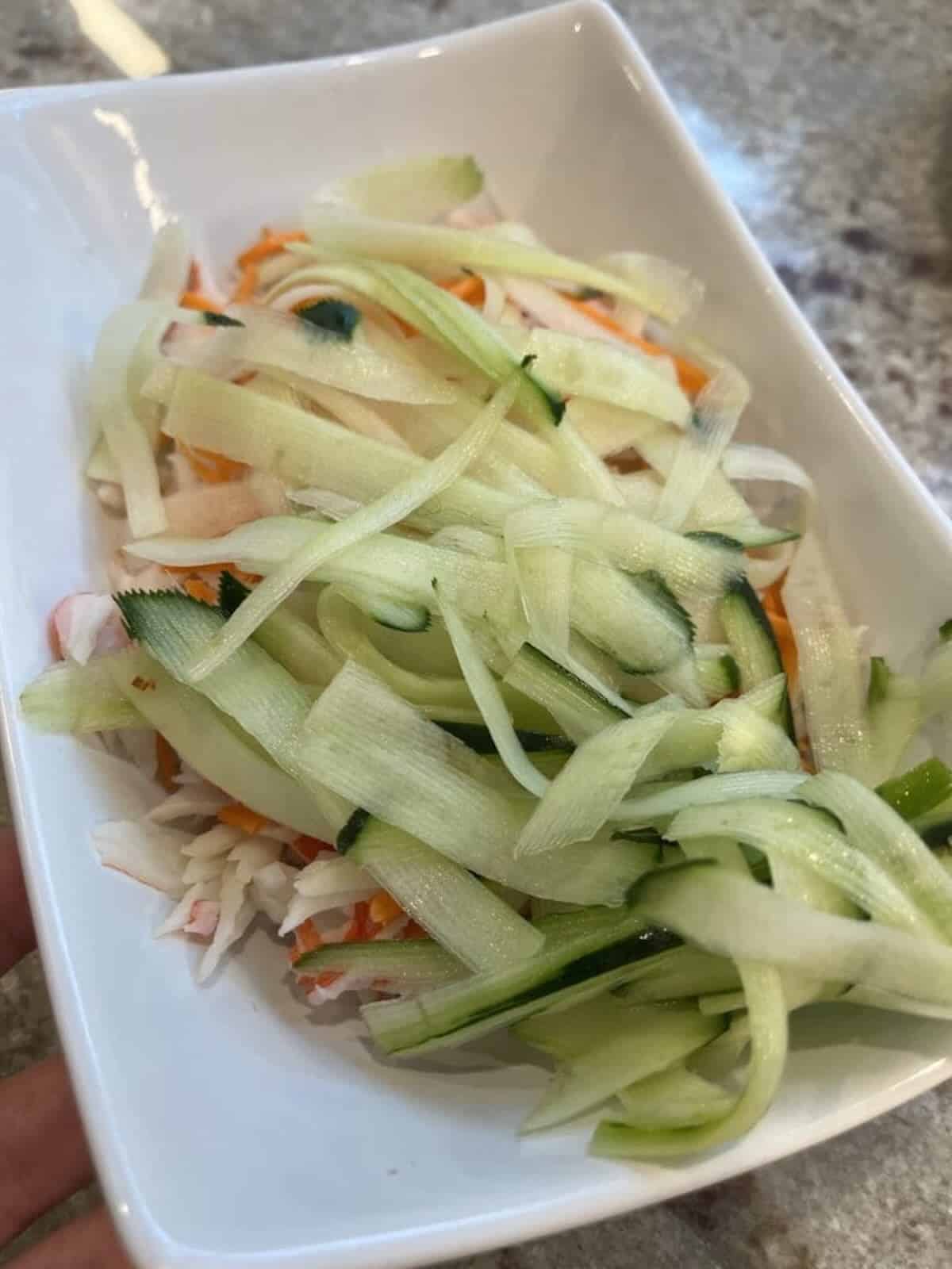 shredded imitation crab, cucumber and carrot in a bowl.