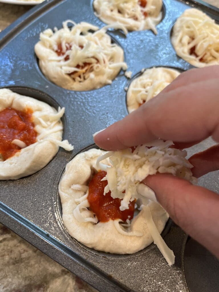 cheese going onto pizzas 