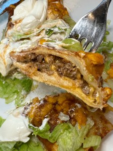 enchirito with lettuce and sour cream sliced open