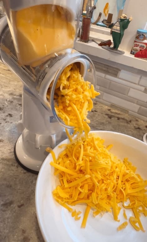 shredded cheddar cheese going into bowl