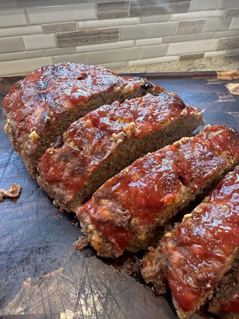 cooked bacon cheeseburger meatloaf on cutting board sliced