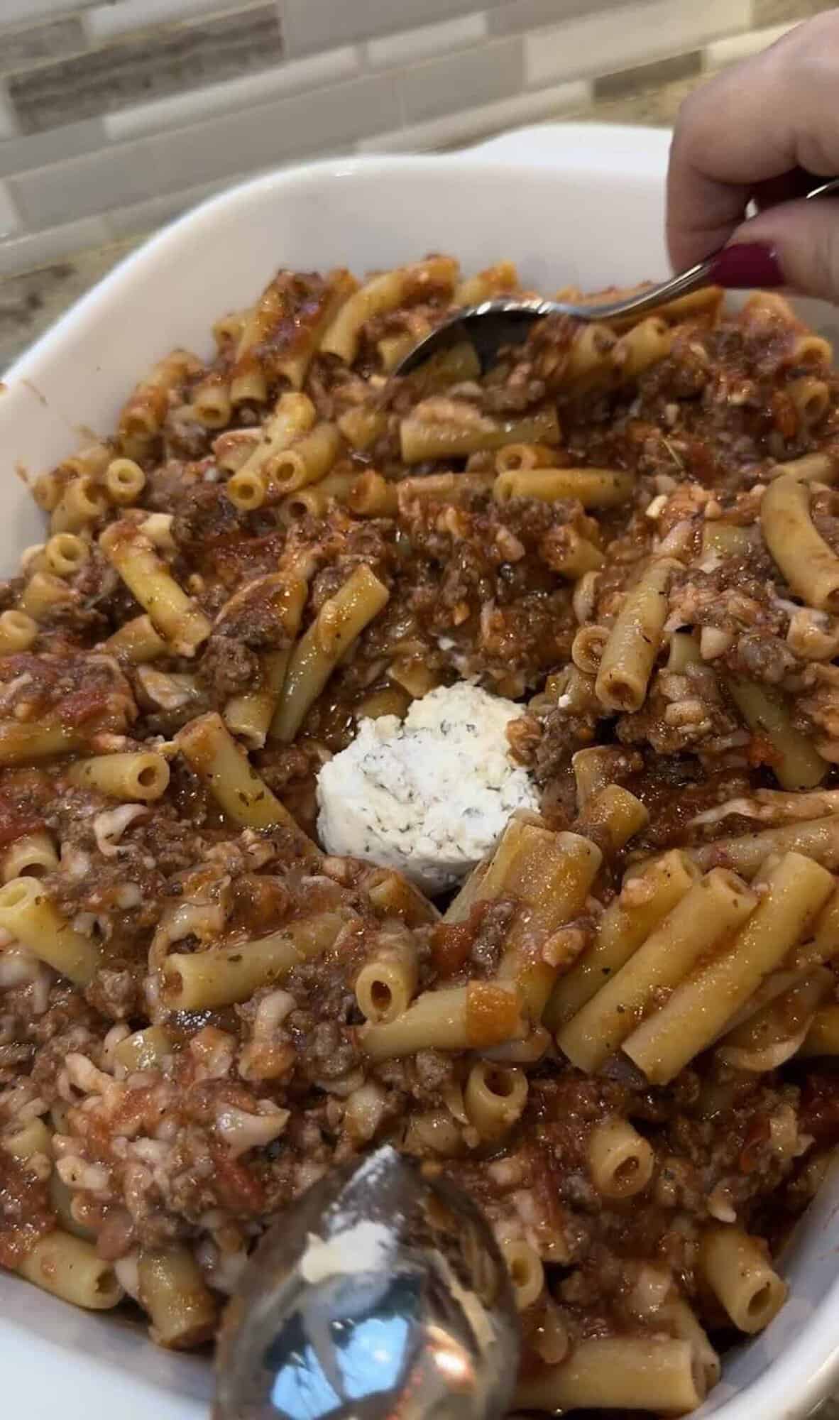 putting ricotta cheese dollops on ziti before baking