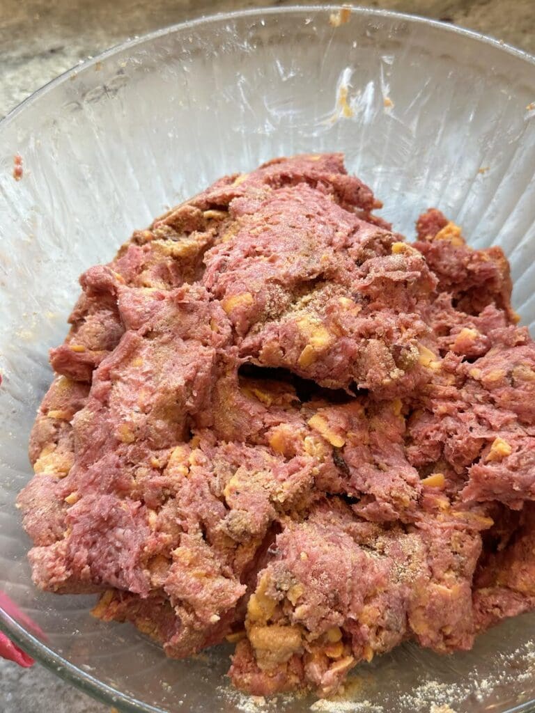 seasoned ground beef, bacon, and shredded cheese mixed together in bowl