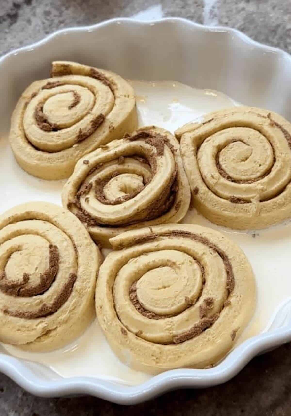 cinnamon rolls in baking dish with heavy cream