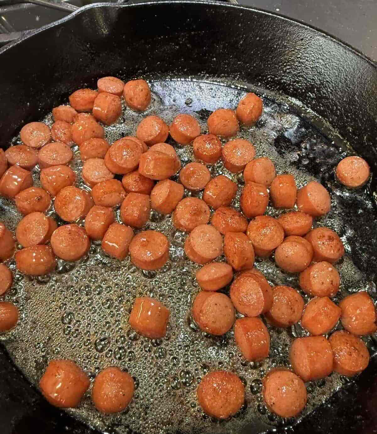 hot dogs browning in cast iron skillet