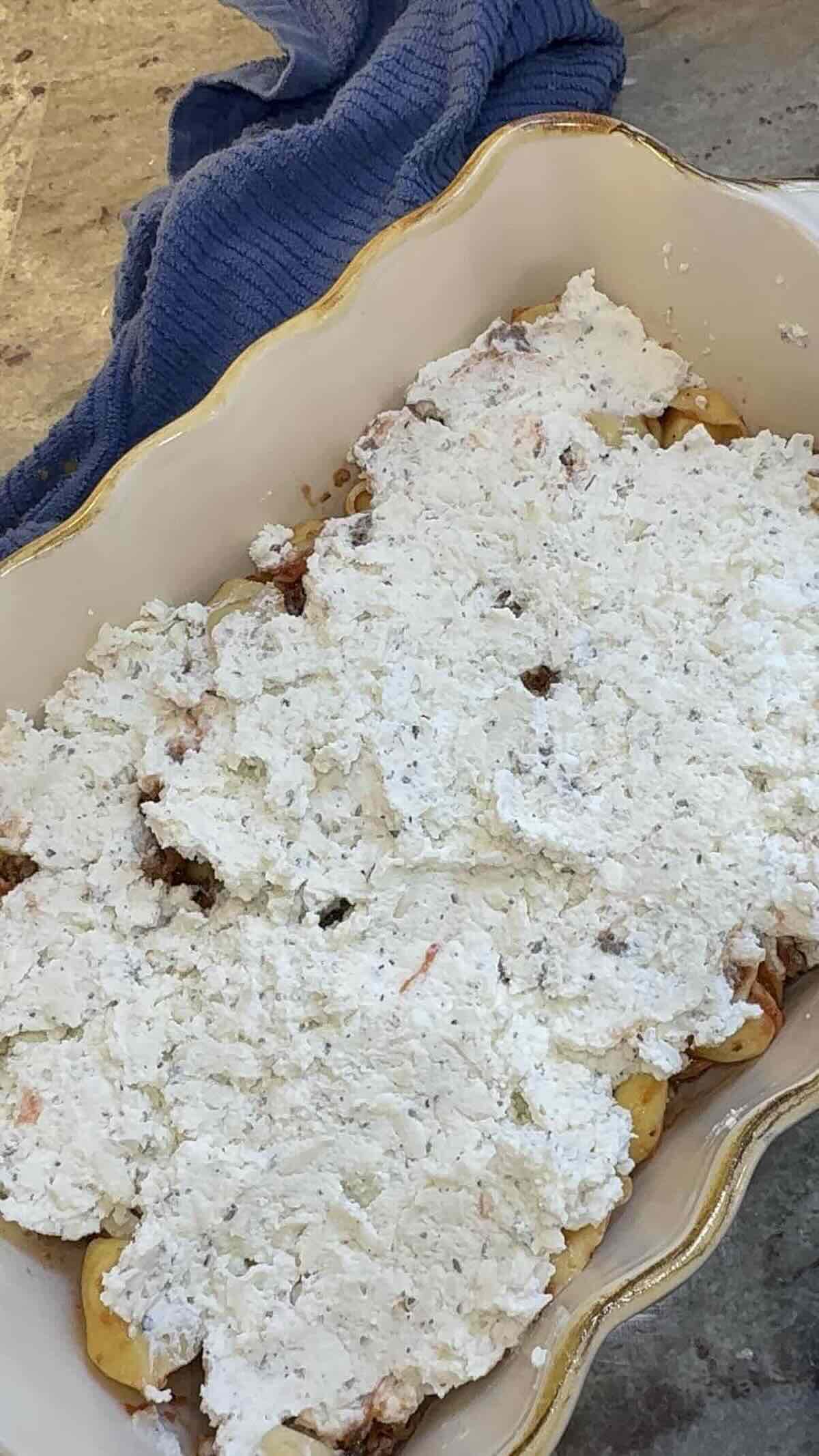 tortellini and meat sauce in skillet with ricotta cheese on top