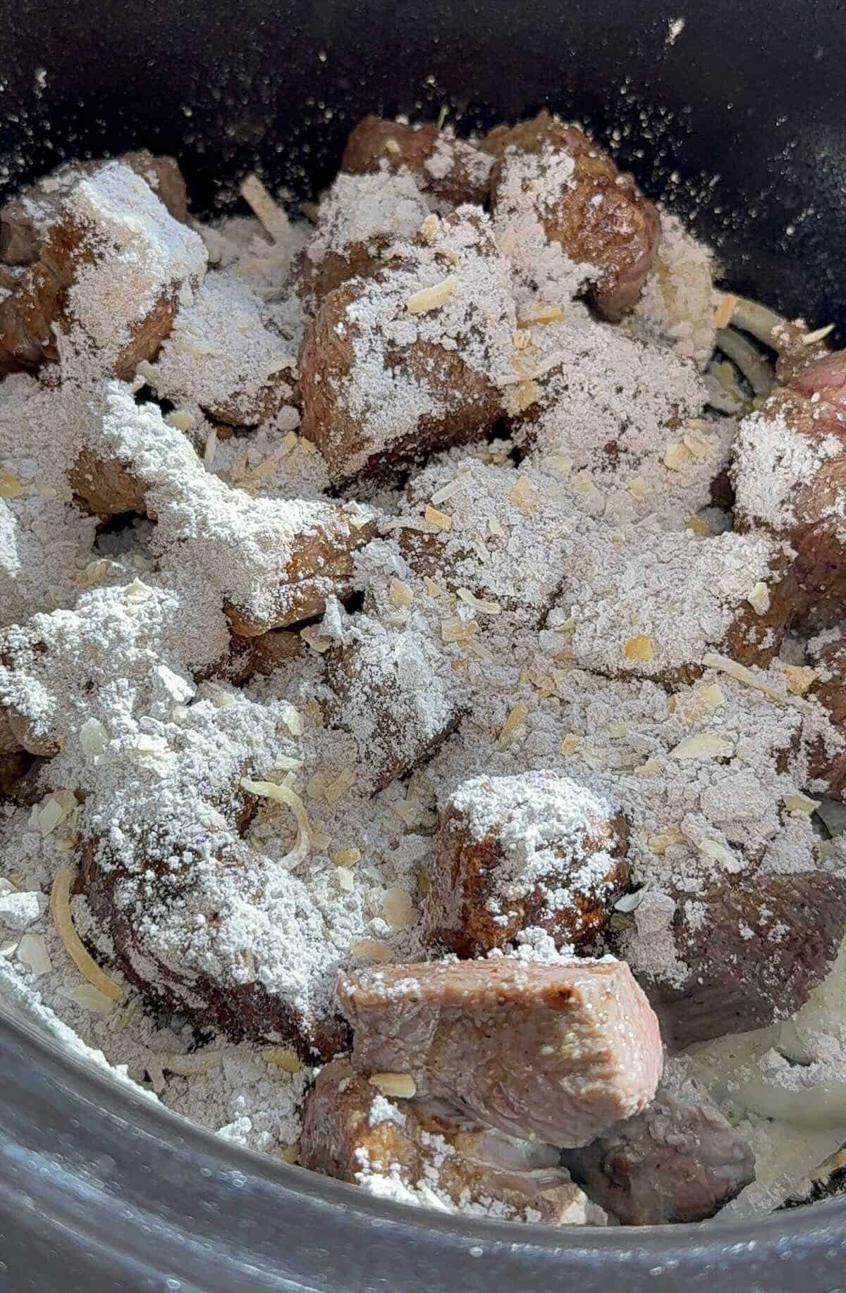 chuck roast on top of onions in the crockpot with seasoning packets