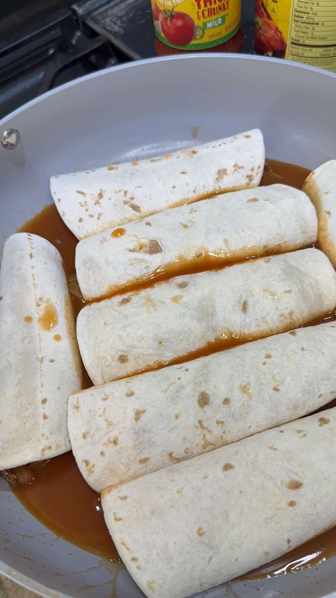 rolled enchiladas in the skillet with enchilada sauce