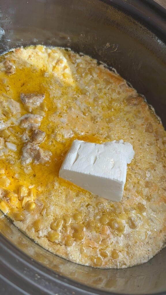 adding cream cheese to the half cooked street corn chicken