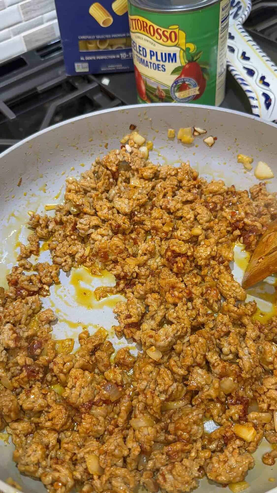 cooked sausage in a skillet with onion and garlic