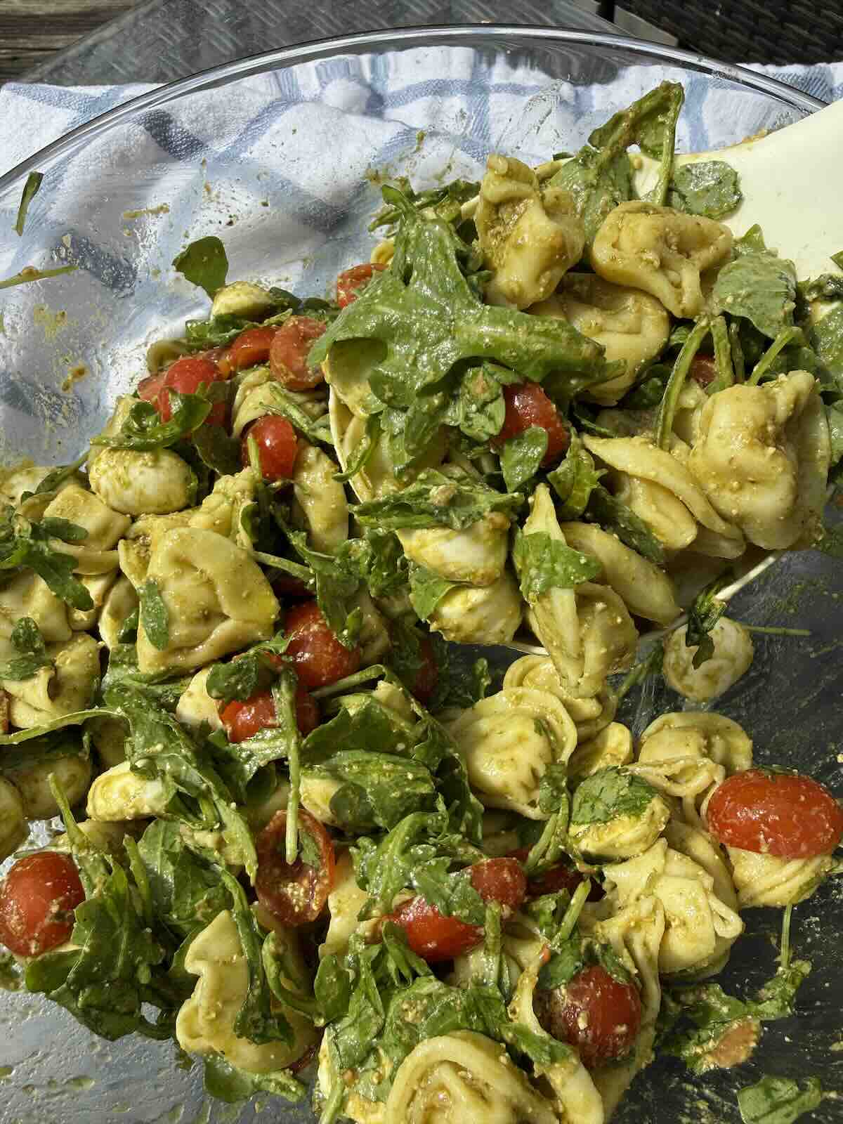 caprese pesto tortellini salad ingredients mixed in a bowl